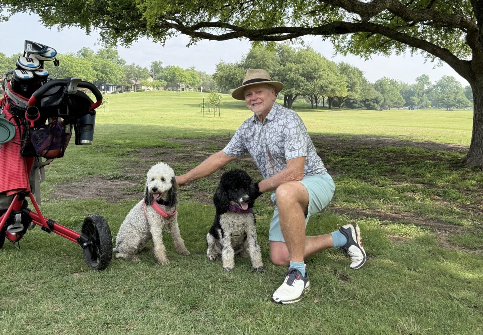 IMG_5031 A man kneeling down next to two dogs.