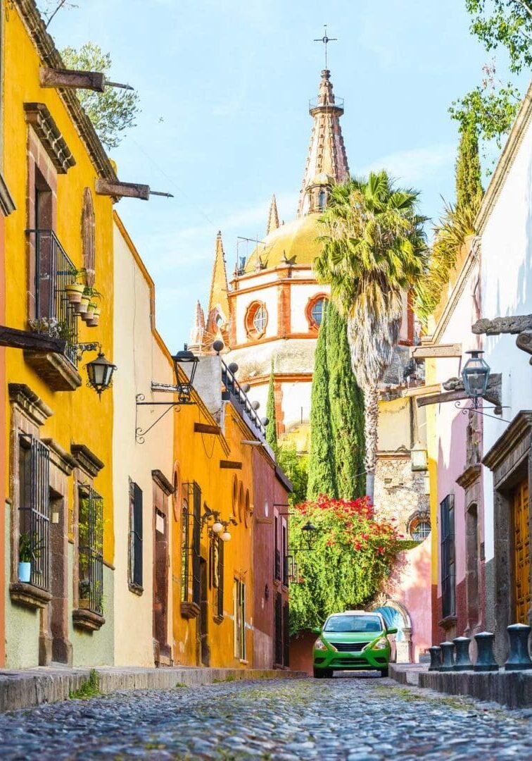 67c9f353c3c0e_mexico_san-miguel- A street with many buildings and trees in the background